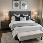 Спальня в современном стиле, серо-синяя цветовая гамма, большая кровать с изголовьем, прикроватные тумбочки, декоративные подушки, ковер.