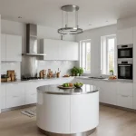 Современная белая кухня с круглым островом, встроенной техникой и светлым деревянным полом.