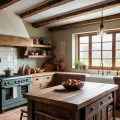 Кухня в стиле прованс, деревянные балки, светлый кухонный гарнитур, керамическая плитка, деревянный остров, окно с видом на сад.