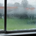 Фотореалистичное изображение поврежденного стеклопакета в пластиковом окне с видимыми трещинами и инеем, демонстрирующее необходимость замены.