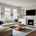 Гостиная в светлых тонах, большой угловой диван, камин, телевизор, книжные полки, ковер.