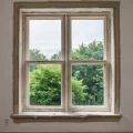 Фотореалистичное изображение окна с только что нанесенной шпаклевкой на откосах, демонстрирующее процесс ремонта и улучшения дома своими руками при ярком дневном свете.